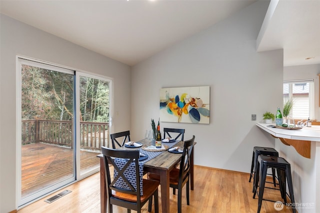 dining room featuring visible vents, vaulted ceiling, light wood-style flooring, and baseboards