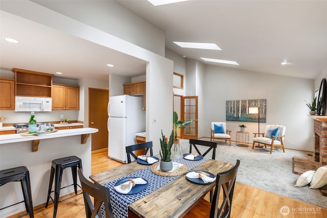 dining room with lofted ceiling with skylight, light wood-type flooring, and recessed lighting