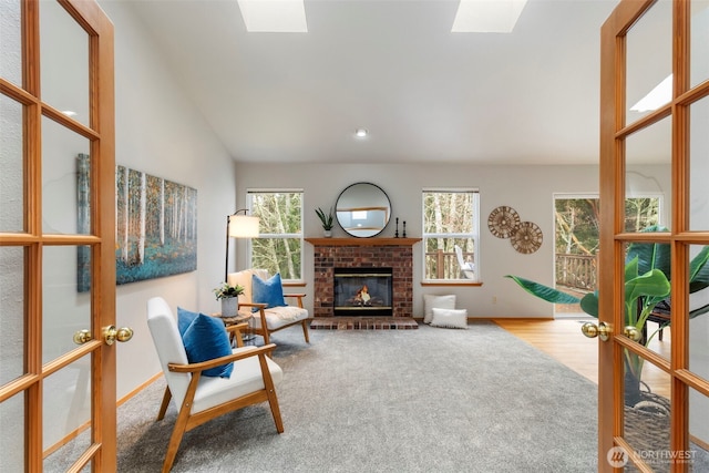 sitting room featuring carpet, french doors, lofted ceiling with skylight, and a fireplace