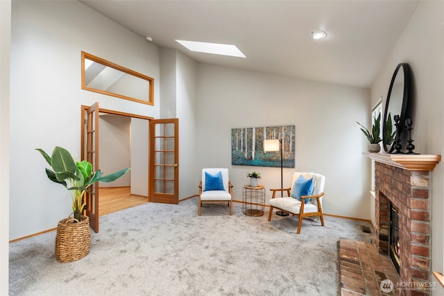 sitting room with lofted ceiling with skylight, a fireplace, carpet flooring, and baseboards