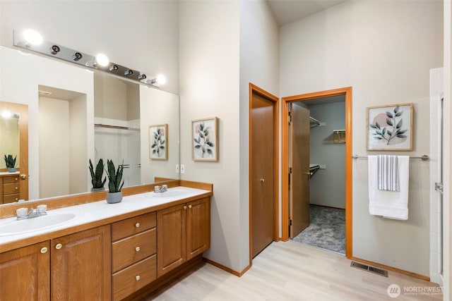 full bath with wood finished floors, visible vents, a sink, and double vanity