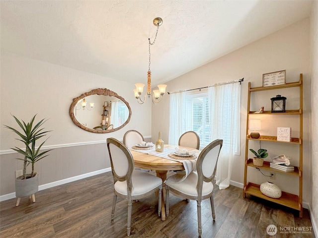 dining area featuring a notable chandelier, vaulted ceiling, a textured ceiling, and wood finished floors