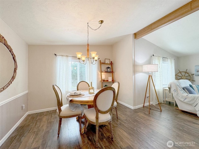 dining space featuring baseboards, lofted ceiling with beams, wood finished floors, a textured ceiling, and a chandelier