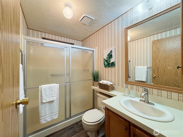 full bathroom with a textured ceiling, a stall shower, and wallpapered walls