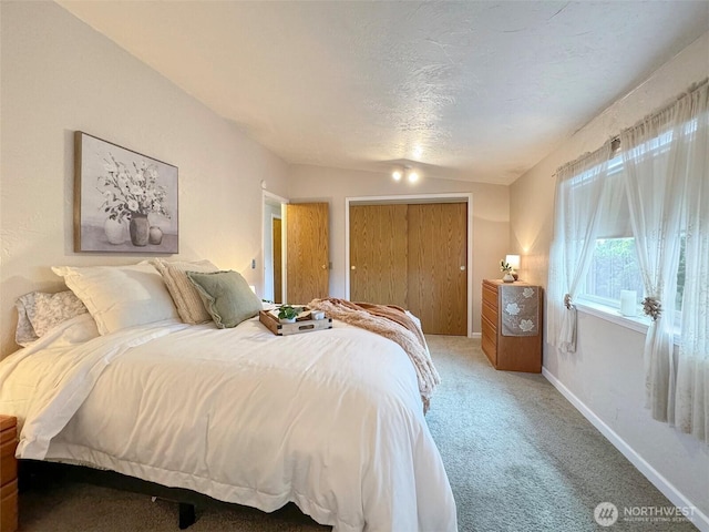 bedroom with light carpet, a closet, a textured ceiling, and baseboards