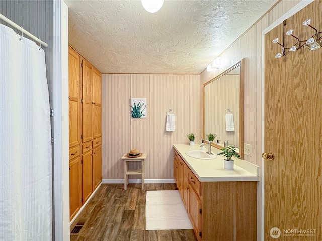 full bath featuring a textured ceiling, wood finished floors, vanity, baseboards, and a shower with curtain