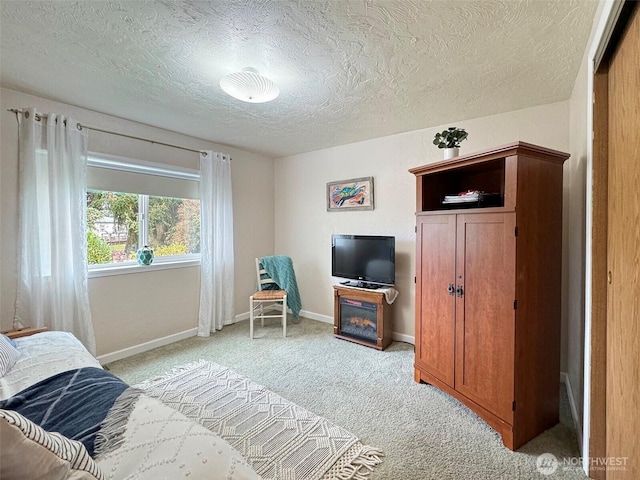 bedroom with light carpet, baseboards, and a textured ceiling