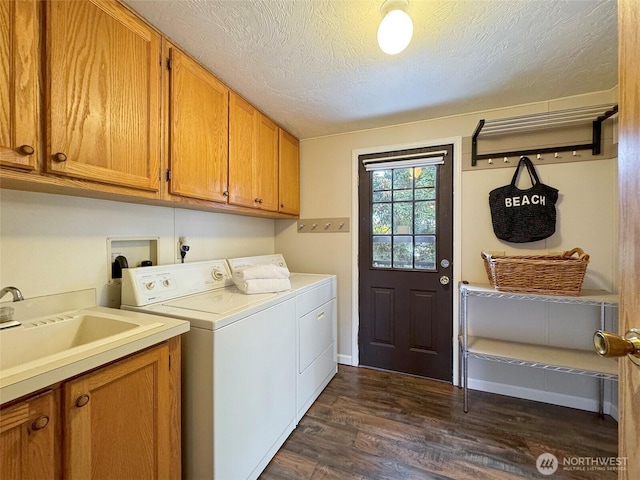 laundry room with dark wood-style floors, cabinet space, a sink, a textured ceiling, and separate washer and dryer