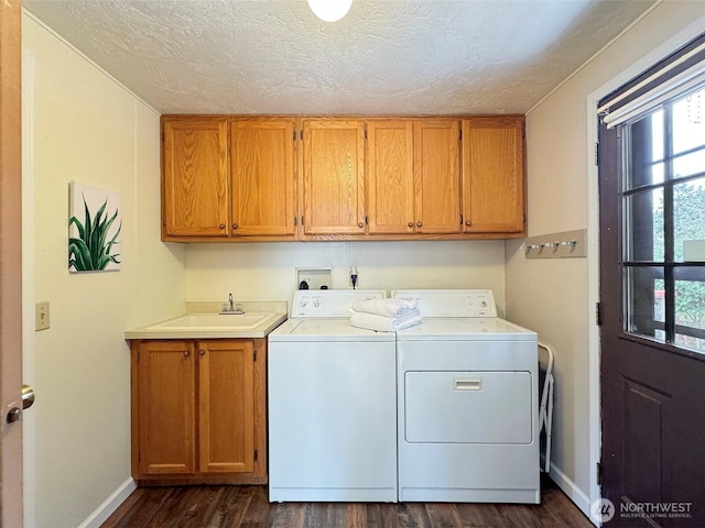 clothes washing area featuring a textured ceiling, a sink, cabinet space, dark wood-style floors, and washing machine and clothes dryer