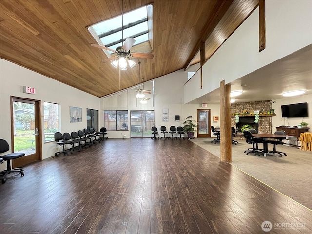 gym featuring high vaulted ceiling, wood ceiling, a large fireplace, and hardwood / wood-style flooring