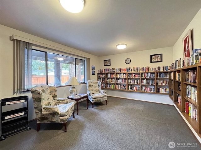 sitting room featuring bookshelves and carpet flooring