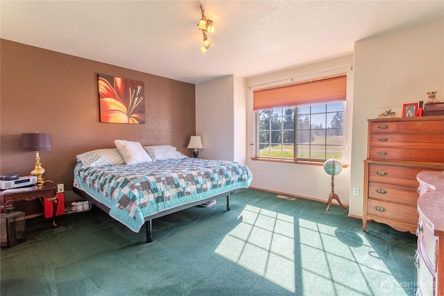 carpeted bedroom with rail lighting, visible vents, and baseboards