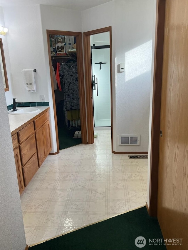 bathroom with a spacious closet, visible vents, vanity, and tile patterned floors