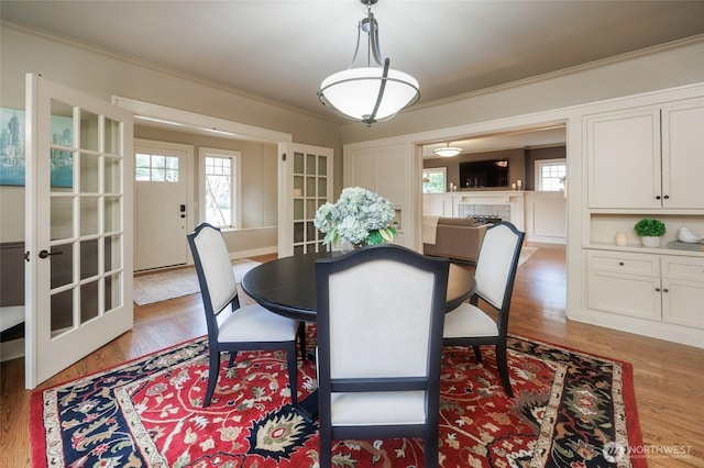 dining area featuring french doors, ornamental molding, plenty of natural light, and wood finished floors