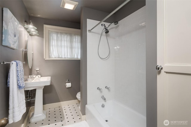 bathroom with toilet, baseboards, a sink, and shower / bathing tub combination