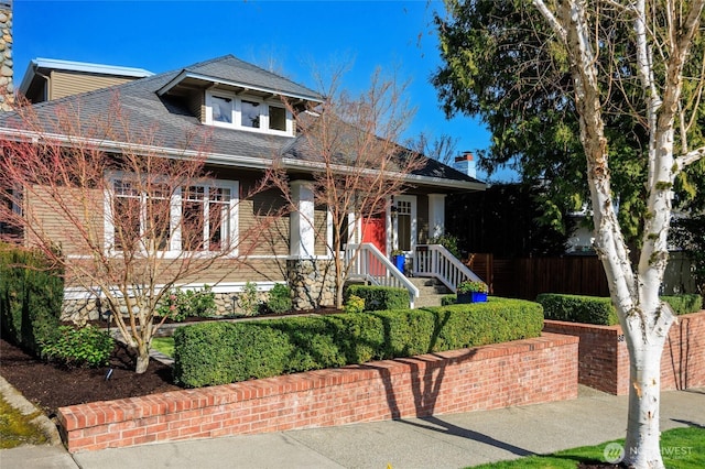 view of front of home with roof with shingles and fence