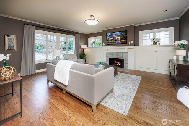 living area with a fireplace, wood finished floors, and crown molding