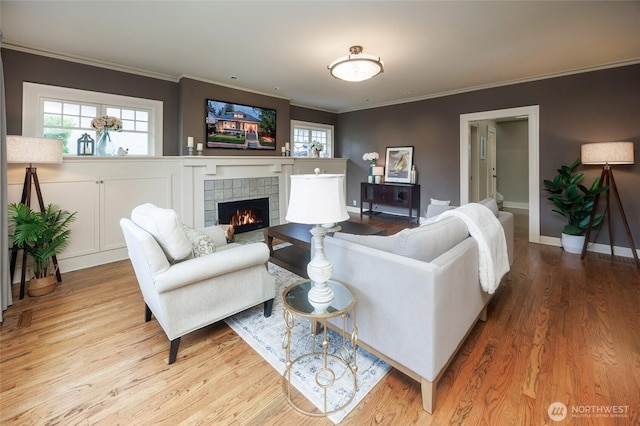 living room featuring crown molding, a fireplace, baseboards, and wood finished floors