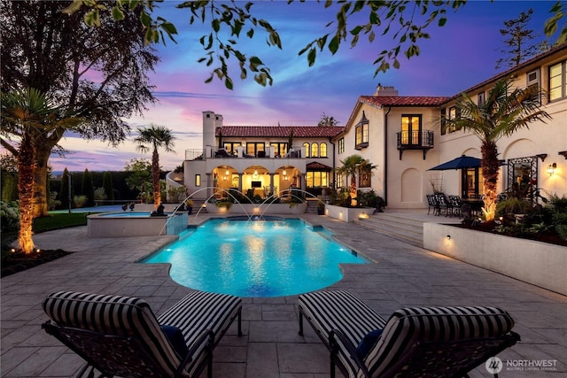 pool at dusk with an in ground hot tub, a patio, and an outdoor pool