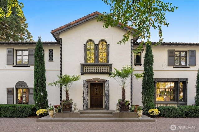 mediterranean / spanish house featuring a tiled roof and stucco siding