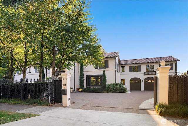 view of front of house featuring driveway, a garage, a tiled roof, fence, and stucco siding