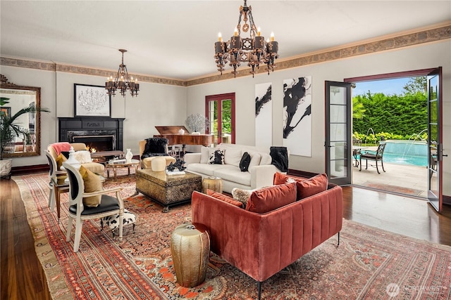 living area with a chandelier, a warm lit fireplace, and wood finished floors