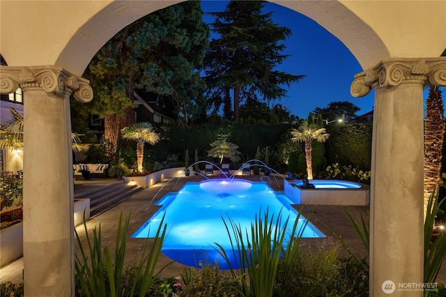 pool at twilight featuring an in ground hot tub and a patio area