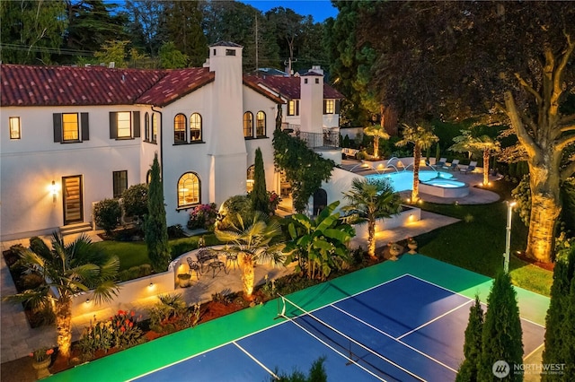 exterior space featuring a tennis court, fence, and an outdoor pool