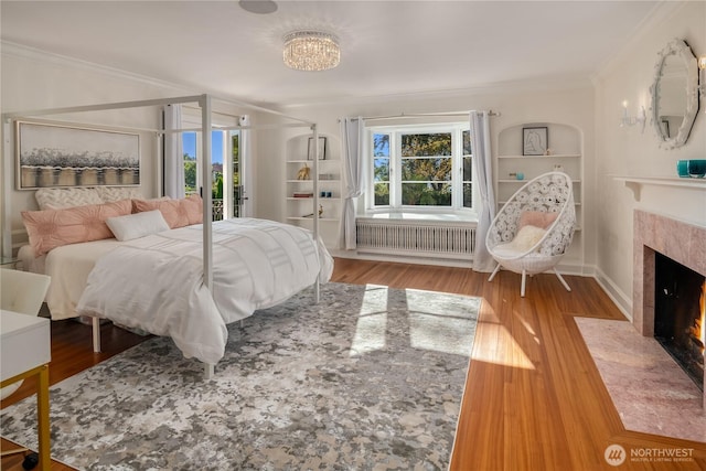 bedroom featuring multiple windows, radiator heating unit, and crown molding