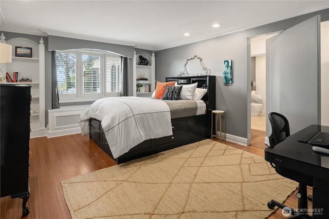 bedroom featuring baseboards, ensuite bath, ornamental molding, wood finished floors, and recessed lighting