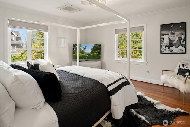 bedroom with crown molding, multiple windows, visible vents, and wood finished floors