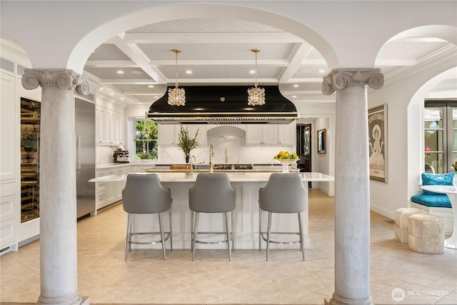 kitchen with a breakfast bar, range hood, coffered ceiling, and beam ceiling