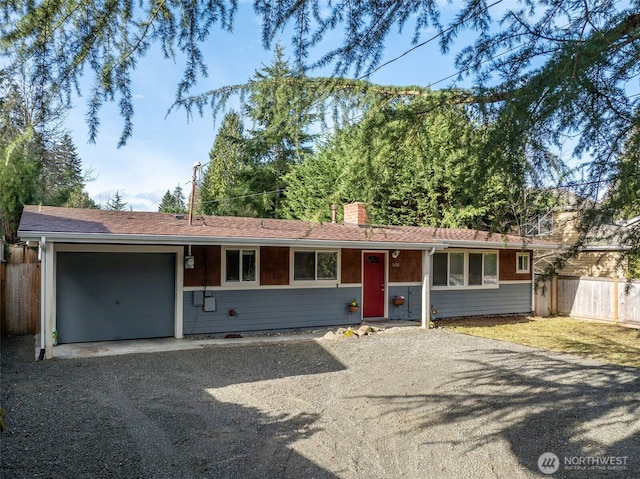 single story home with a chimney, an attached garage, fence, and gravel driveway