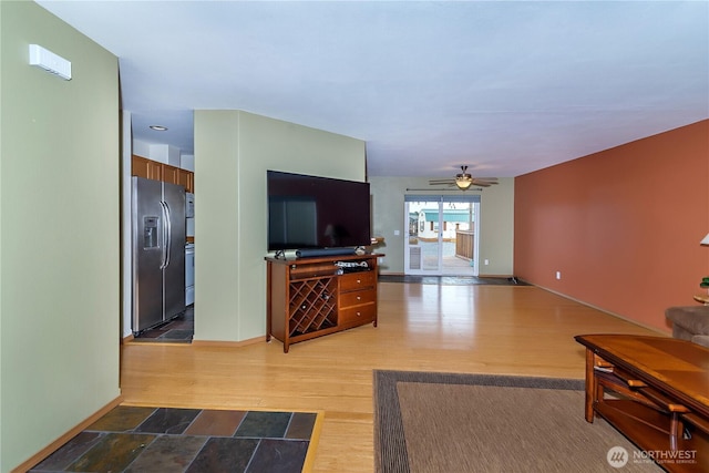 living area with a ceiling fan, wood finished floors, and baseboards