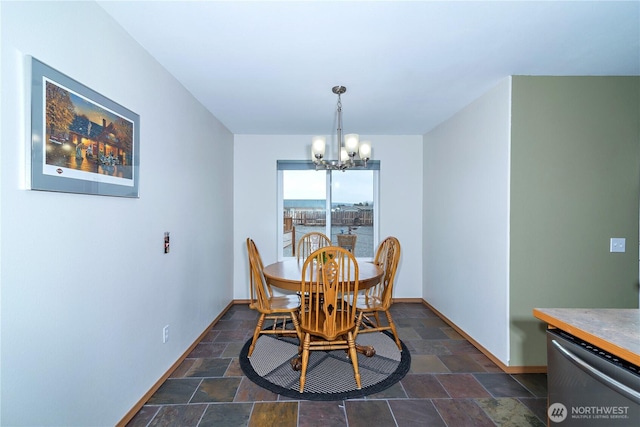 dining space with stone tile flooring, baseboards, and an inviting chandelier