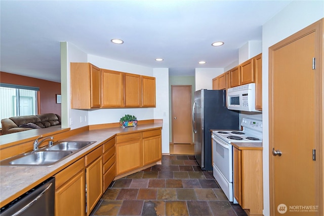 kitchen with recessed lighting, white appliances, stone finish flooring, and a sink