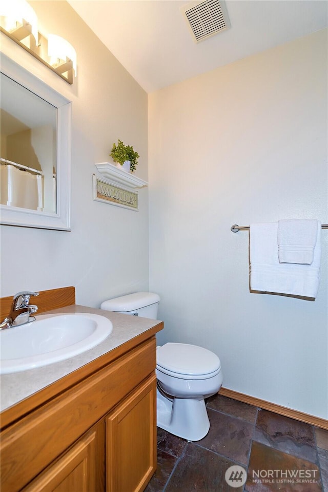 bathroom with visible vents, toilet, vanity, and stone finish flooring