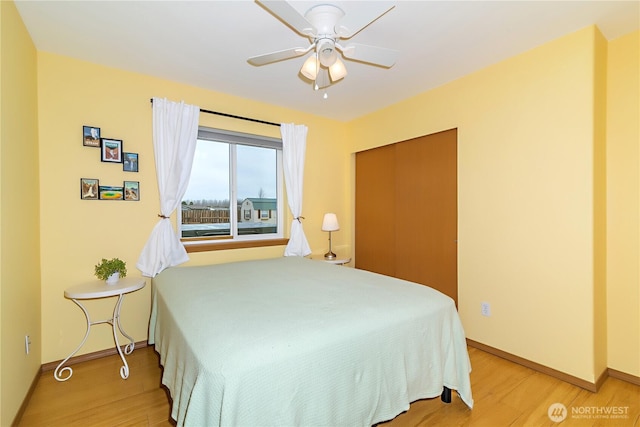 bedroom featuring light wood-type flooring, baseboards, and a ceiling fan