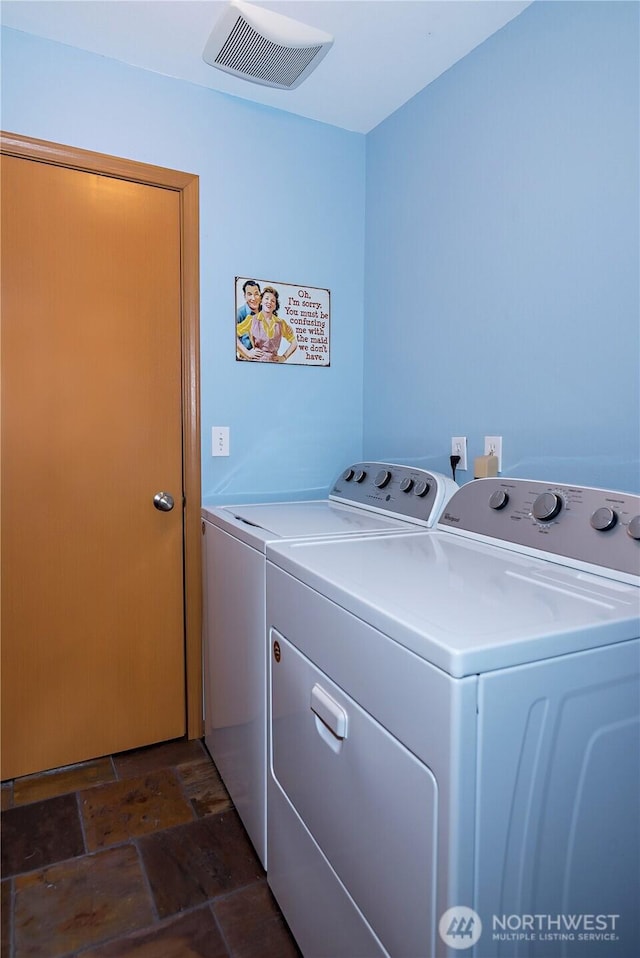 laundry area with laundry area, visible vents, independent washer and dryer, and stone finish flooring