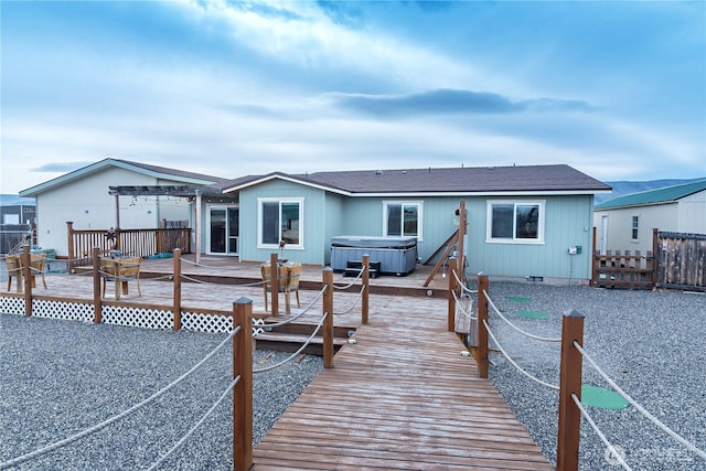 rear view of house featuring a hot tub, fence, a wooden deck, crawl space, and a pergola