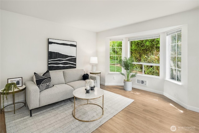 living area with visible vents, light wood-style flooring, and baseboards