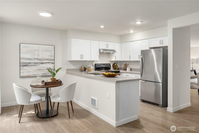 kitchen with black range with electric stovetop, freestanding refrigerator, light countertops, under cabinet range hood, and a sink