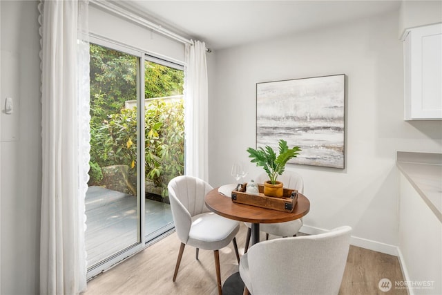 dining area featuring light wood-style floors and baseboards