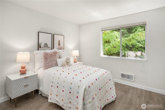 bedroom featuring baseboards, visible vents, and wood finished floors