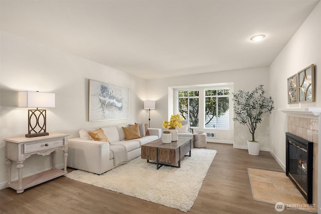 living room with baseboards, wood finished floors, and a tile fireplace