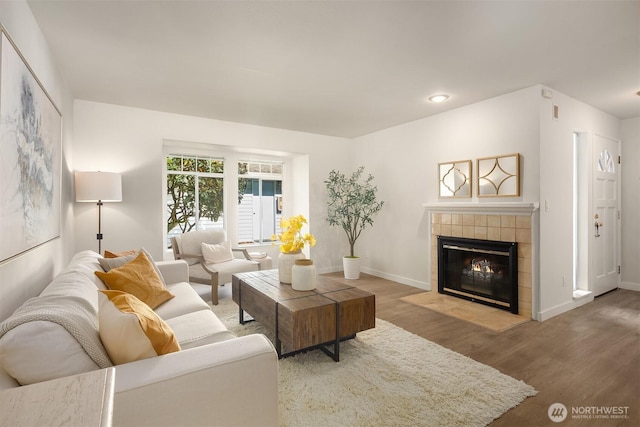 living room with a tiled fireplace, wood finished floors, and baseboards