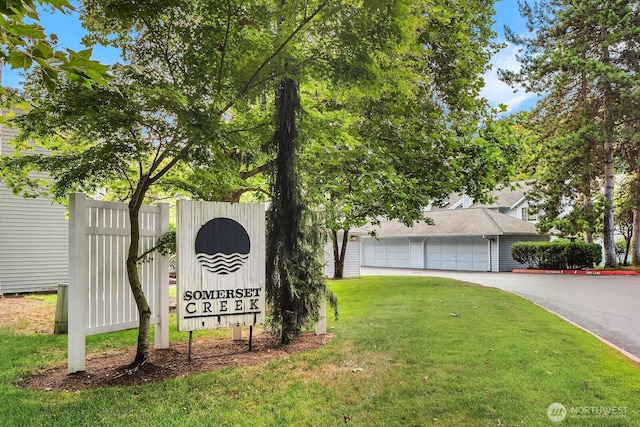 community / neighborhood sign with a yard and driveway