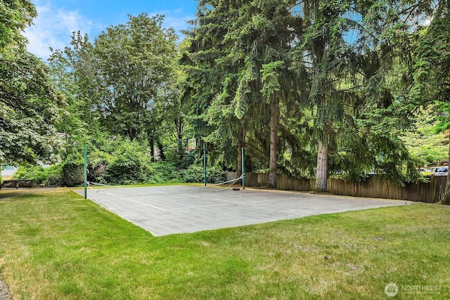 view of sport court featuring basketball hoop, a tennis court, fence, and a lawn