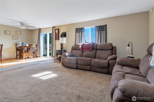 living room featuring carpet floors, a wood stove, and ceiling fan