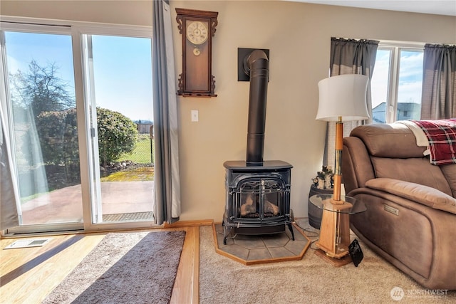 living room featuring a wood stove, visible vents, and wood finished floors